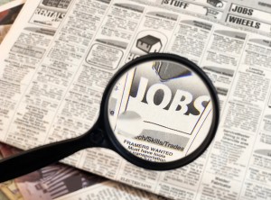 Magnifying glass searching job listings in the newspaper